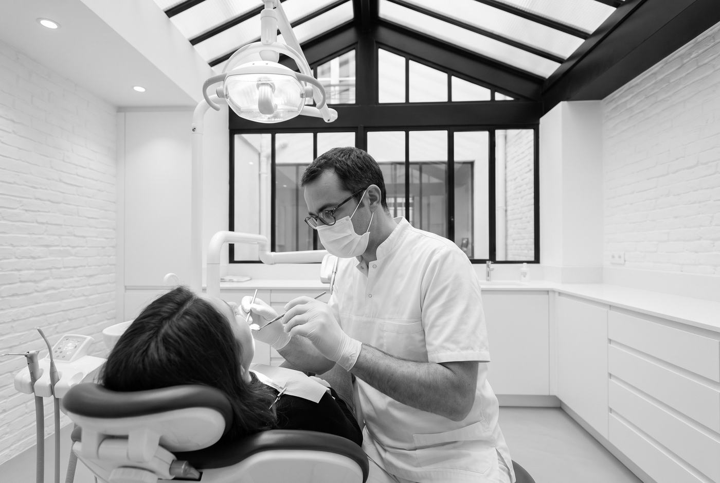 Le Dr Antoine Kervella examine les dents et les gencives d'un patient, sous la verrière