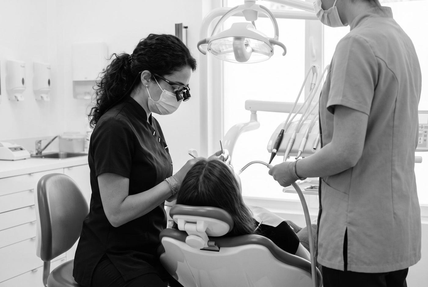 Une chirurgienne-dentiste et son assistante soignent une patiente allongée dans le fauteuil