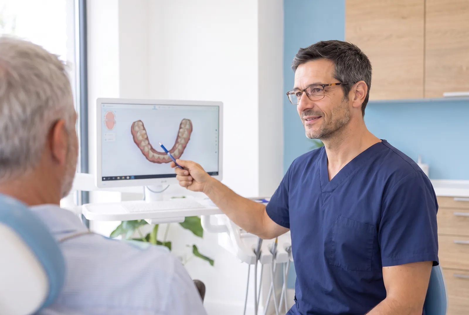 Le Dr Adrien Castel montre à un patient, sur l'écran, l'empreinte numérique en 3D de son arcade