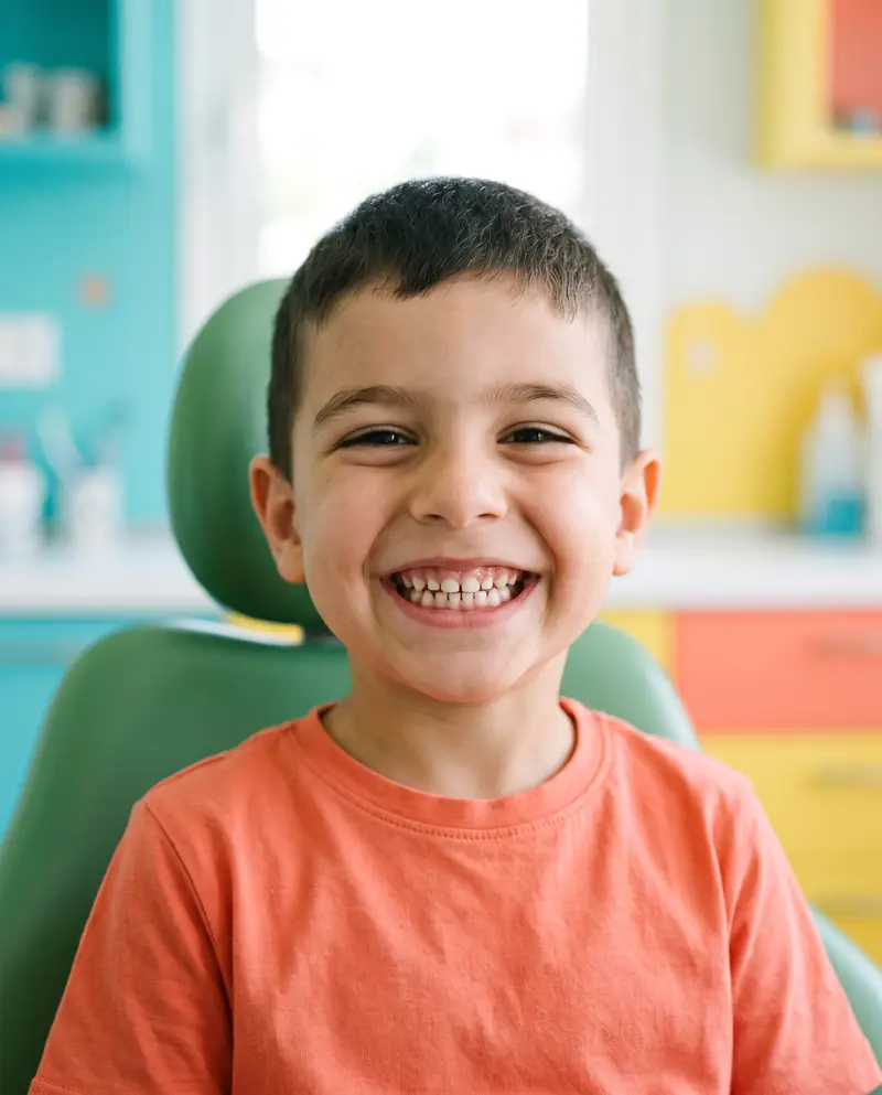 Un garçon de cinq ans rit dans le fauteuil du dentiste.