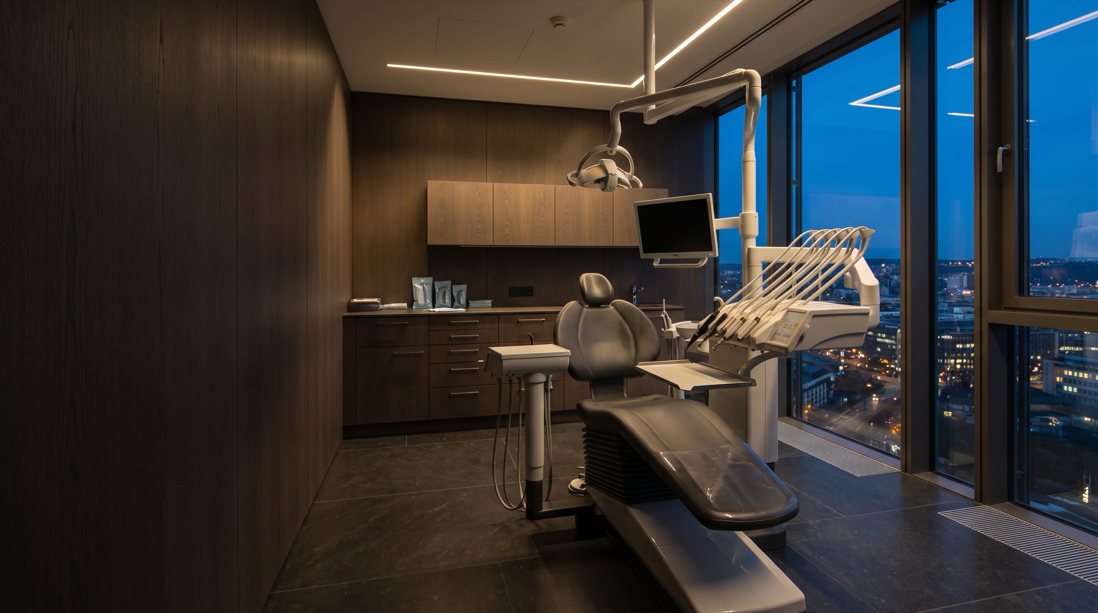 The treatment room at dusk: chair, unit and operating light facing the city lights.