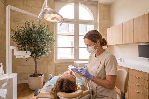 Le Dr Brémond fait le détartrage d'une patiente allongée au fauteuil